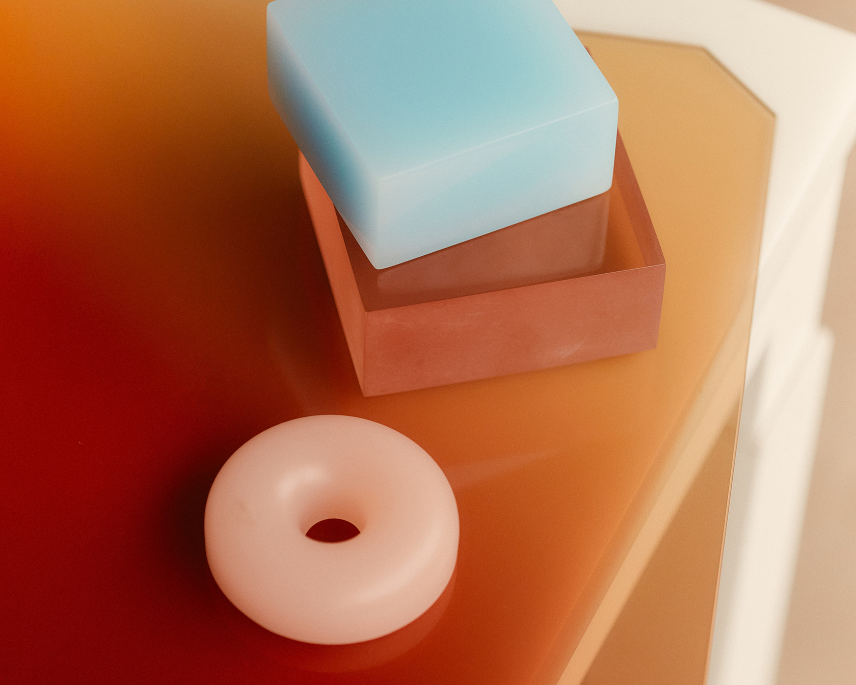 Geometric shapes such as a blue cube and a pink disk on a stylish table top.