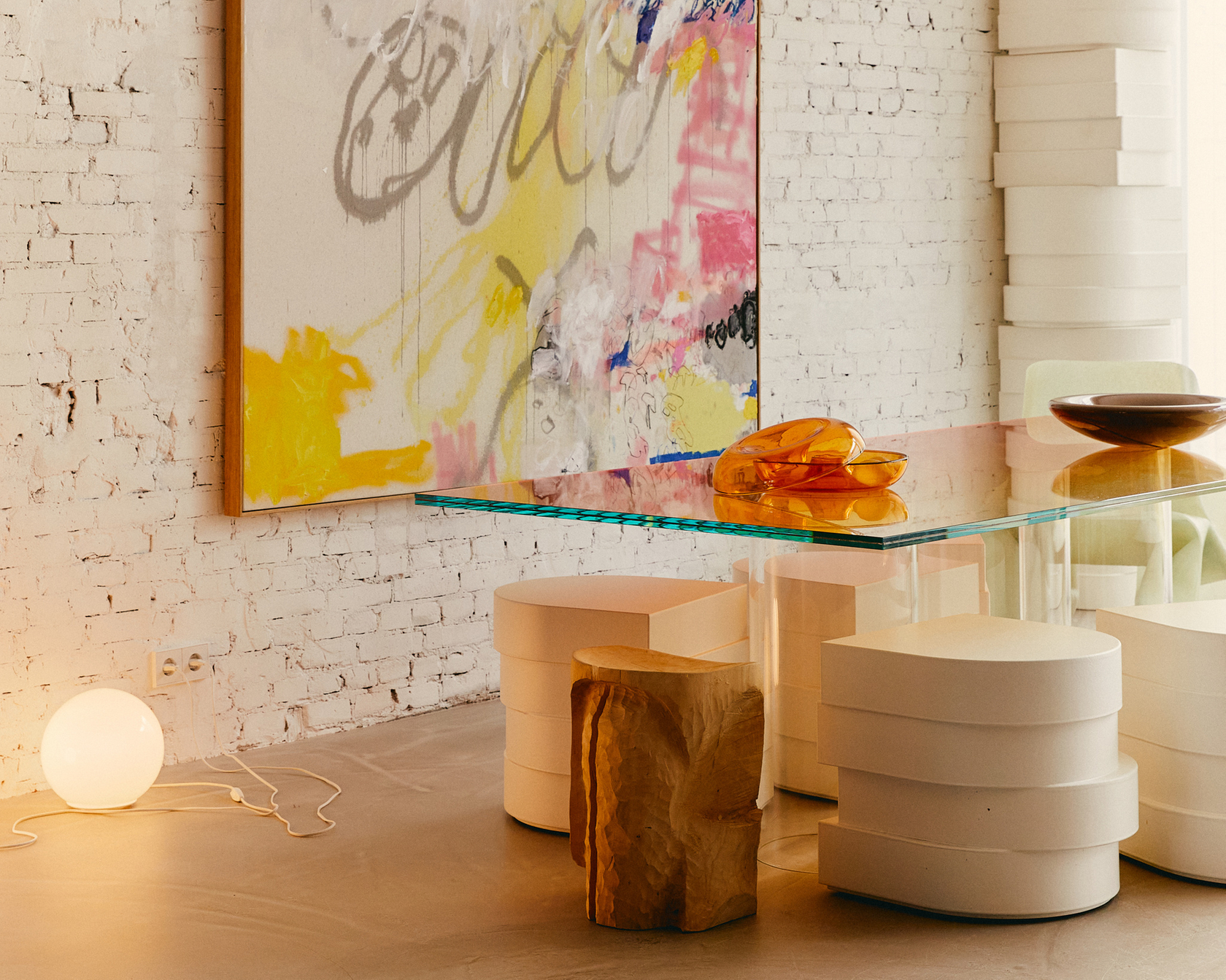 Abstract art on a white brick wall with a modern glass table and stylish furniture in a living room.