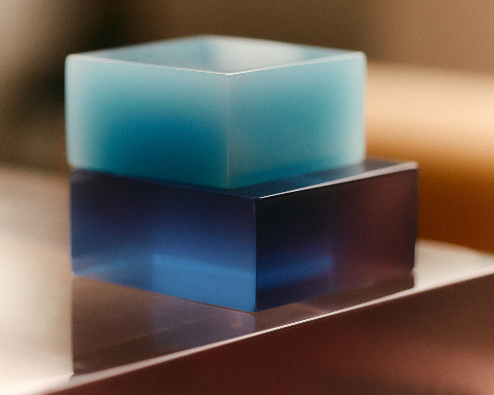Minimalist design with glass cubes in shades of blue and turquoise on a reflective surface.