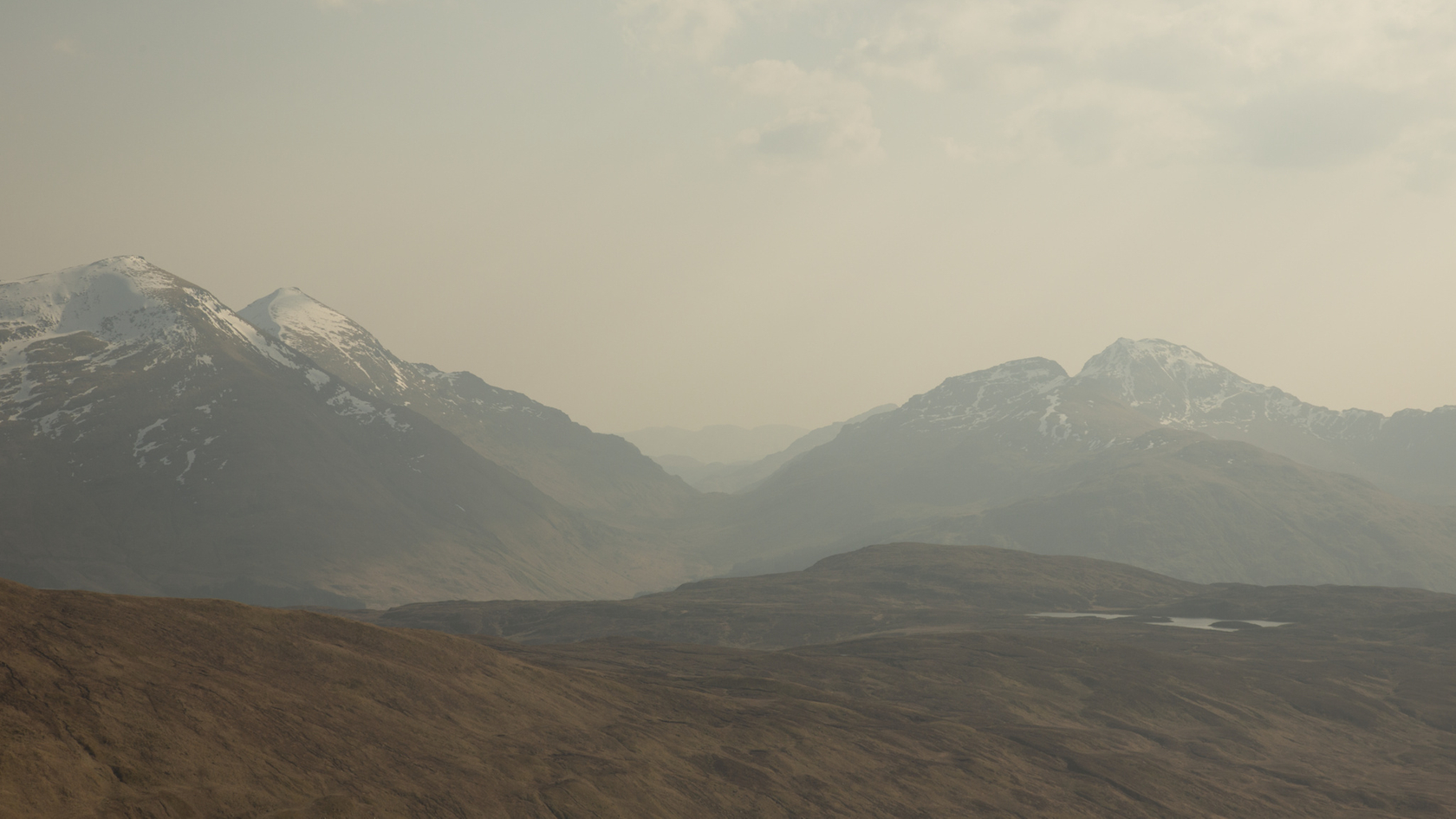 Mountain landscape with snow-covered peaks and rolling hills in the foreground