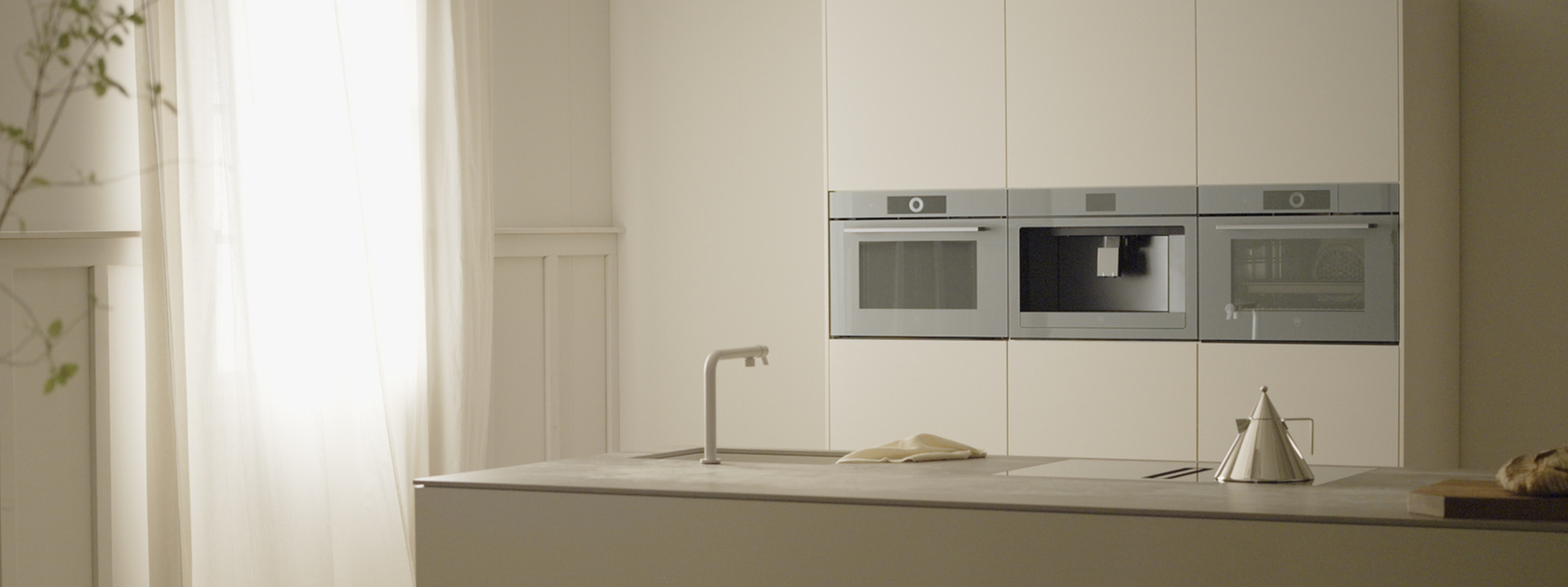 Modern kitchen with built-in appliances such as oven, steamer and coffee machine in a minimalist design