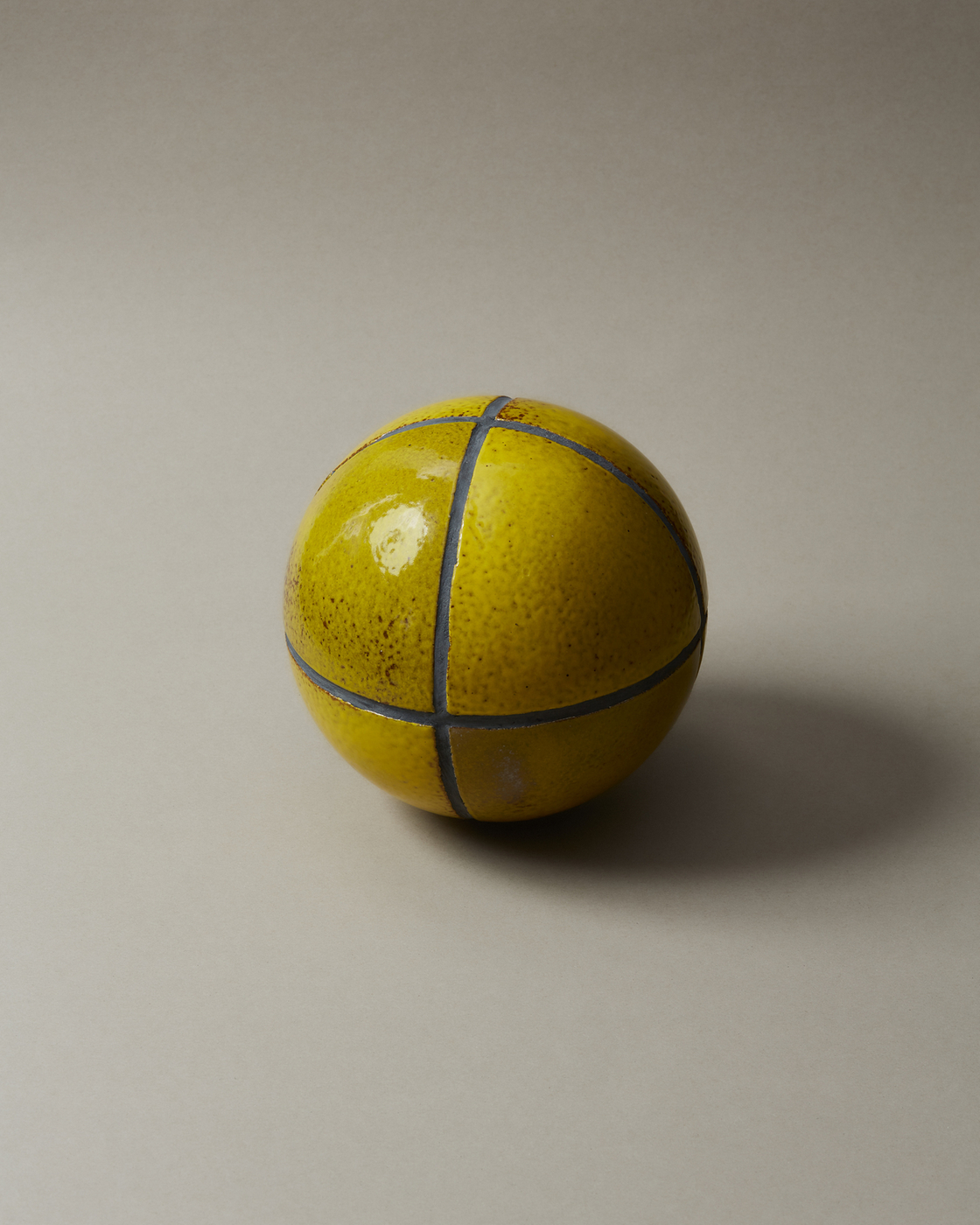 Yellow ceramic ball with blue lines on a beige background