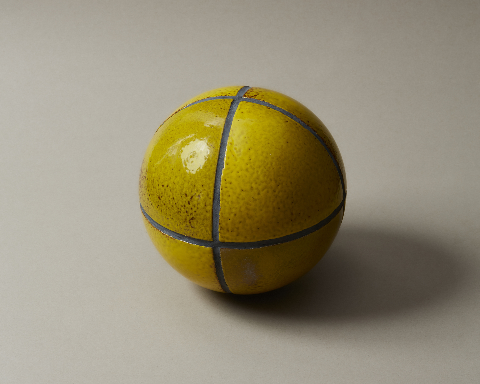 Yellow ceramic ball with blue lines on a beige background