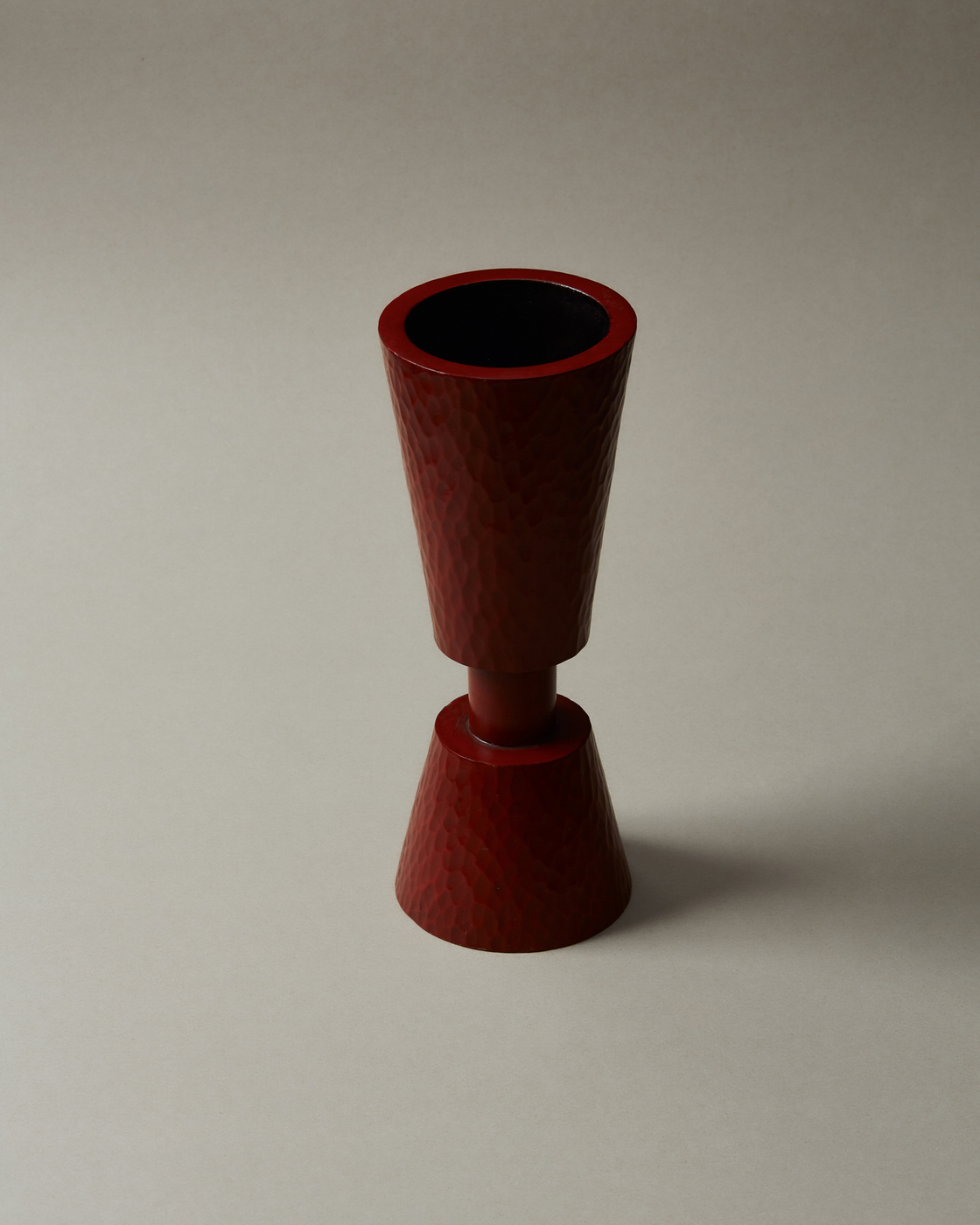 Red hammered vase on a neutral background