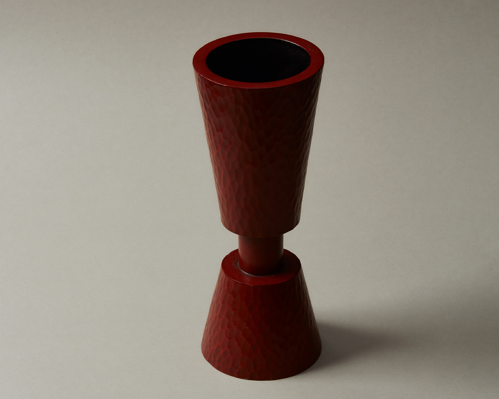 Red hammered vase on a neutral background