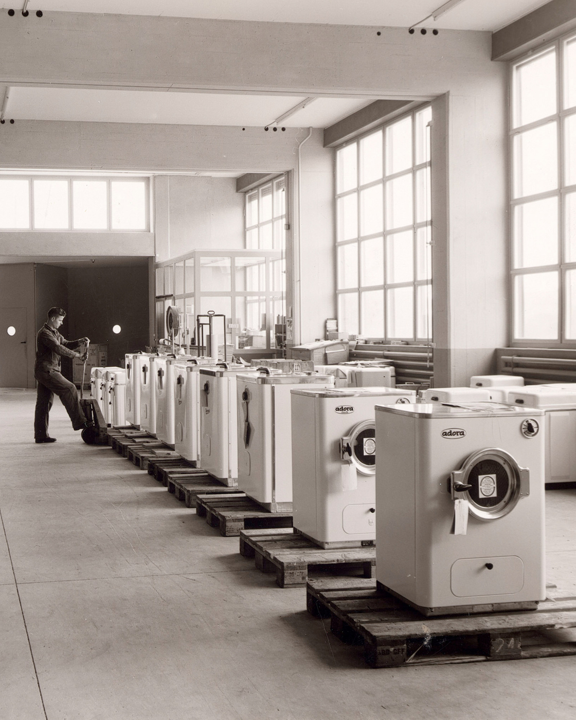 Historic production hall with washing machines and two workers in an industrial setting.
