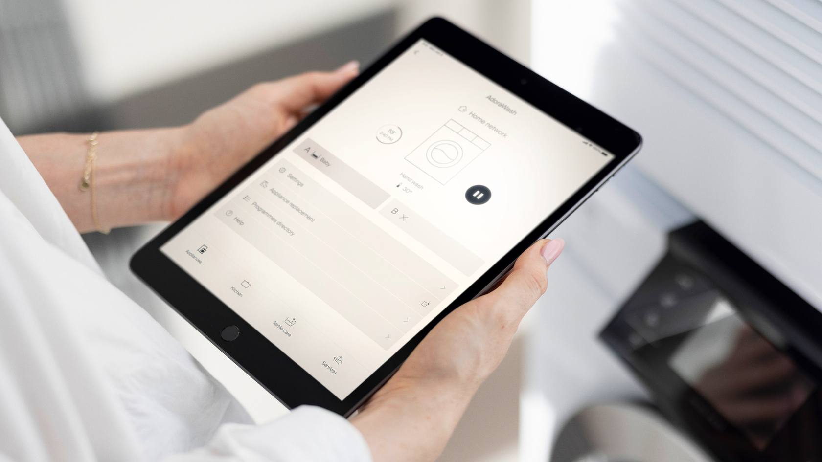 Tablette avec interface utilisateur pour contrôler un lave-vaisselle dans une cuisine moderne.