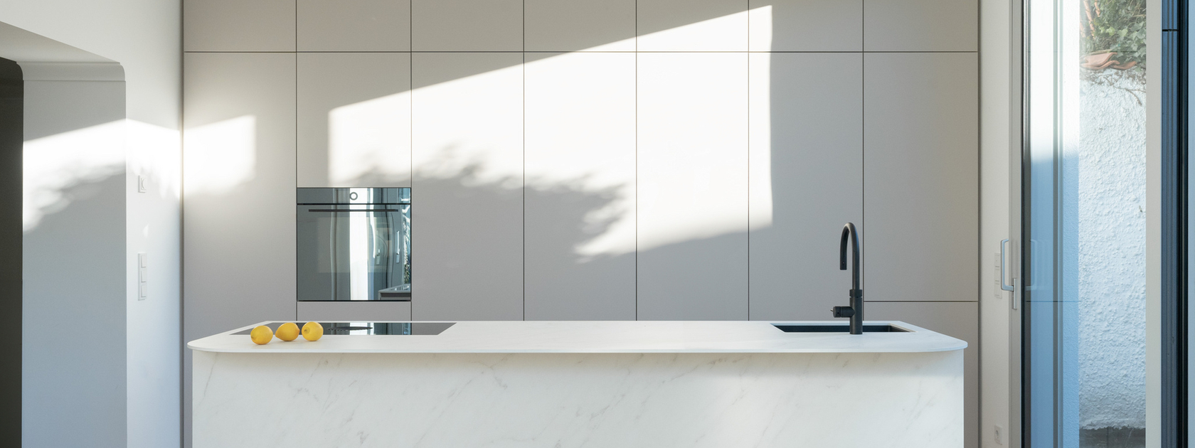 Beyaz pişirme adası, entegre fırın ve minimalist estetiğe sahip modern mutfak