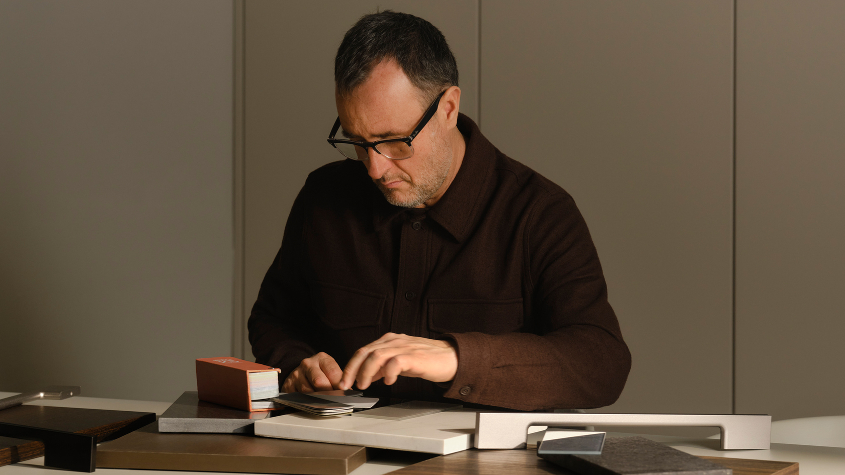 Person am Tisch mit Designmustern und Materialien in einem modernen Raum.