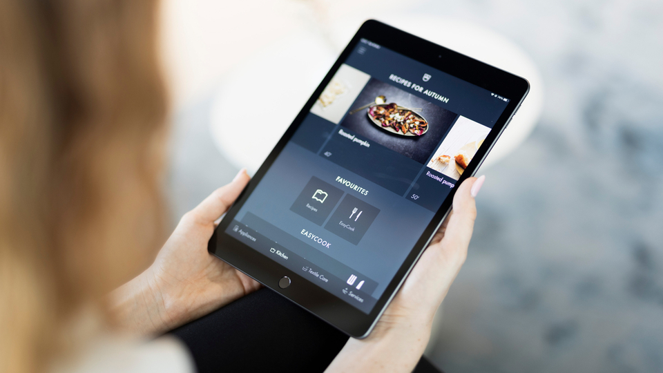 Tablette avec affichage de recettes dans les mains d'une personne montrant l'inspiration culinaire numérique.