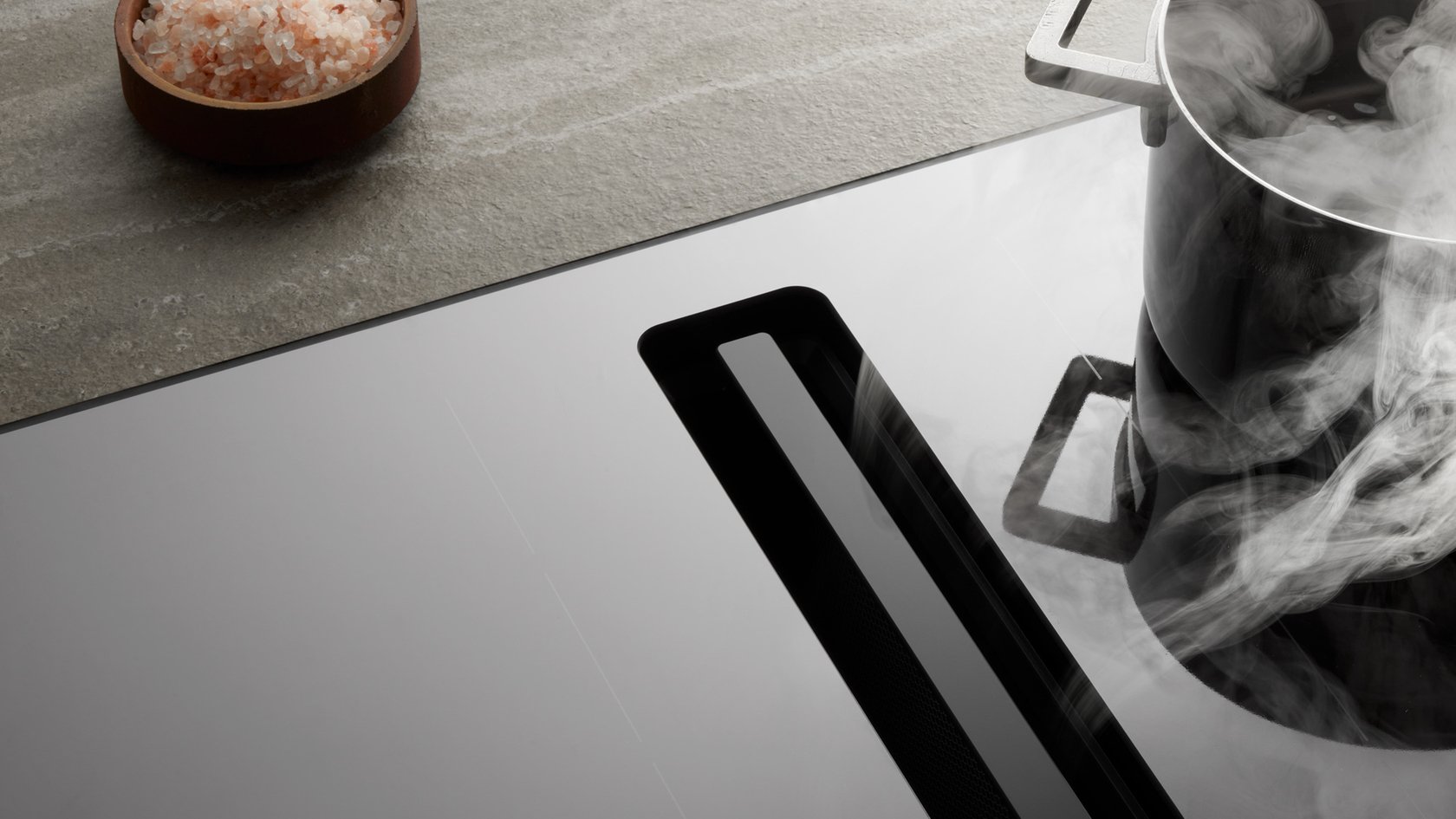 Modern cooktop with integrated extractor fan and steaming saucepan