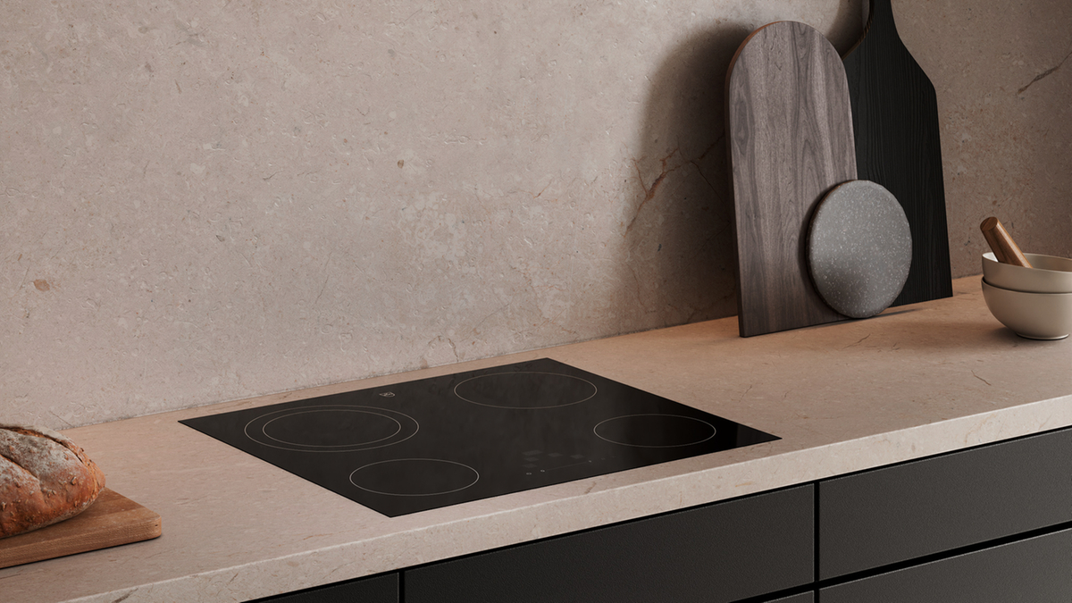 Modernes Kochfeld in einer eleganten Küche mit dunklen Schränken und heller Arbeitsplatte.