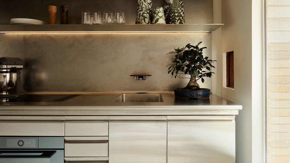 Moderne Küche mit Edelstahloberflächen, eingebautem Backofen und minimalistischer Dekoration