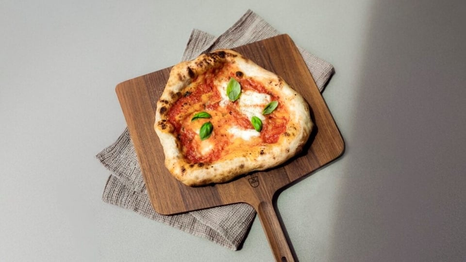 Pizza Margherita su tavola di legno con basilico