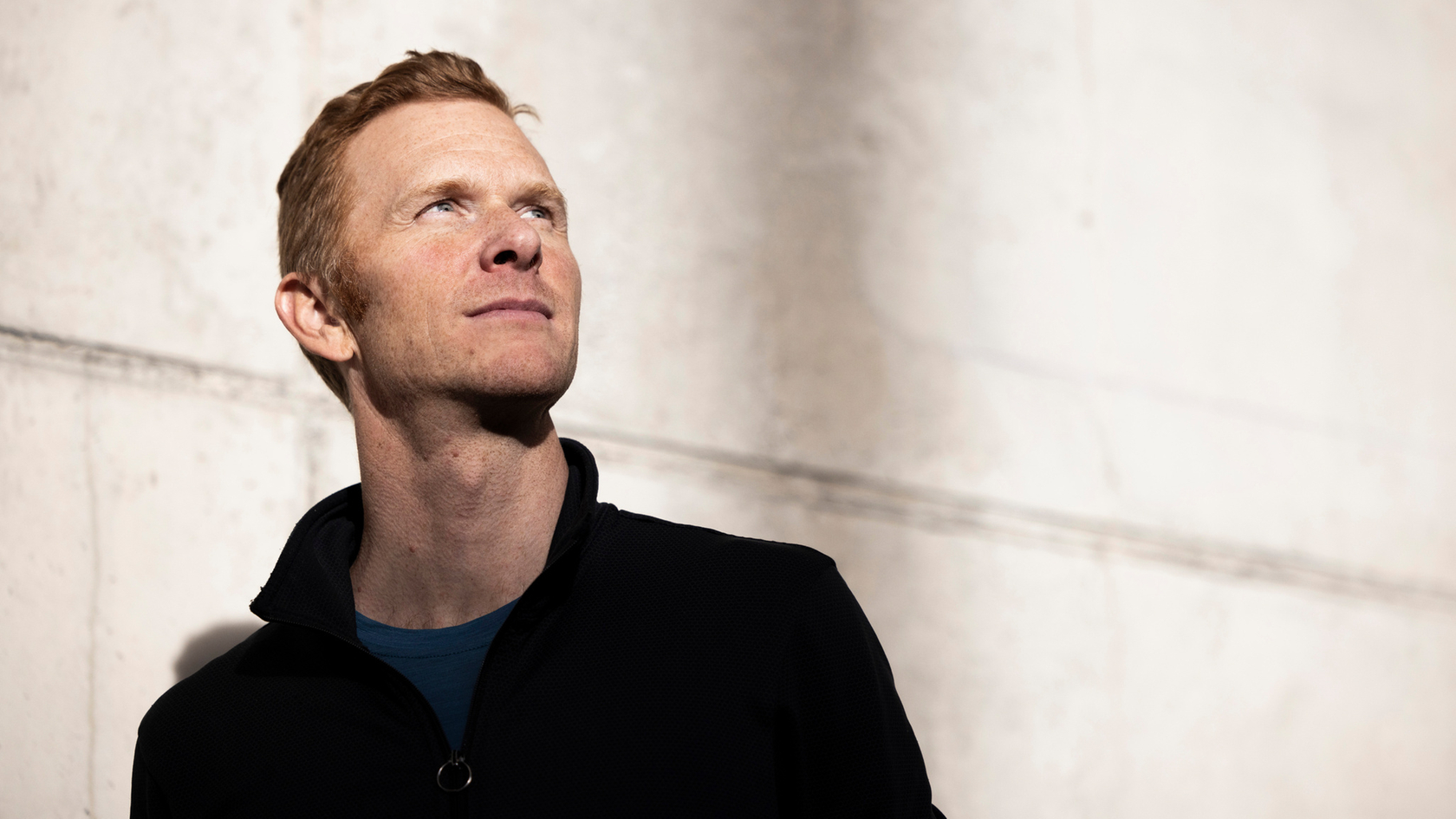 Mann vor einer beleuchteten Betonwand