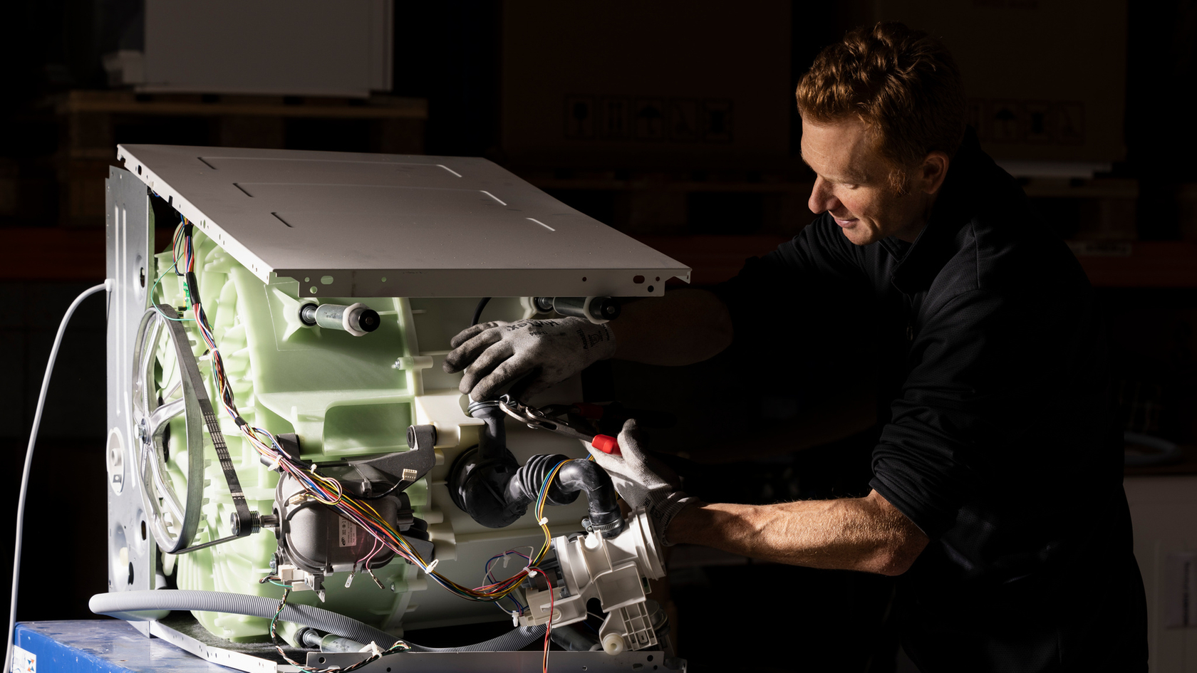 Un tecnico ripara una lavatrice in un'officina.