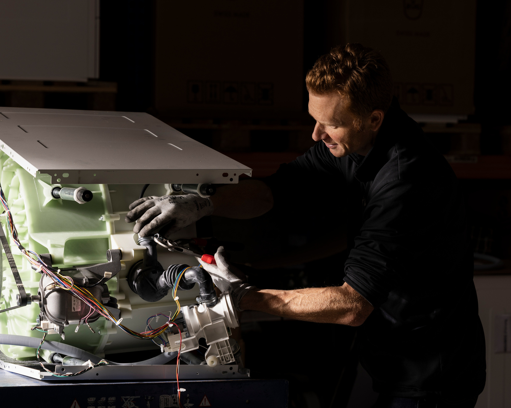 Un tecnico ripara una lavatrice in un'officina.