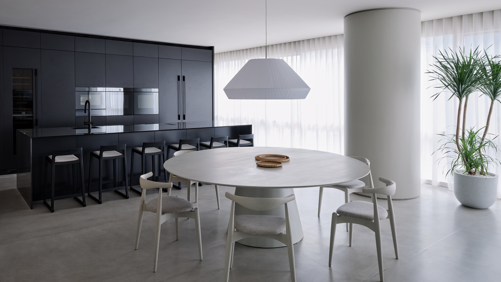 Modern kitchen with black furnishings, kitchen island and round dining table in a bright room