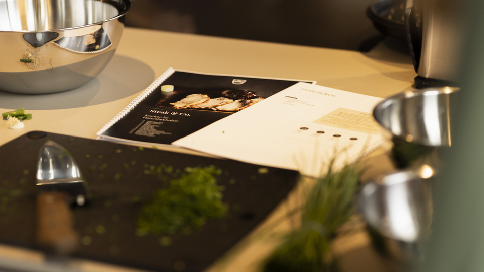 Kitchen accessories with recipe book, cutting board and fresh herbs on a work surface