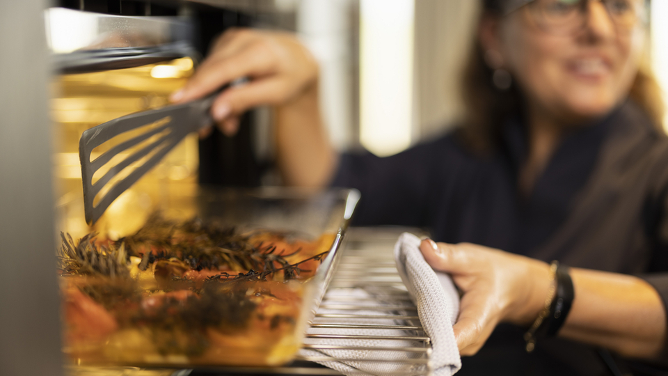 Preparazione di un piatto con erbe e verdure in un forno moderno