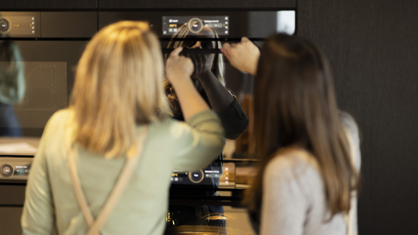 Deux femmes utilisent un four moderne dans une cuisine.