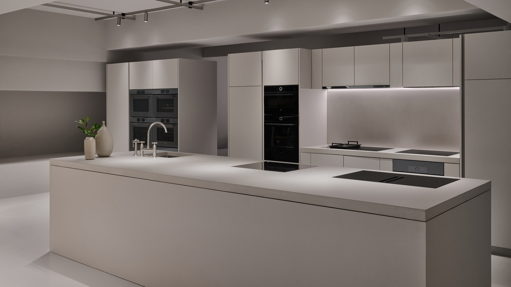 Cucina moderna con isola di cottura, forni a incasso e design minimalista.