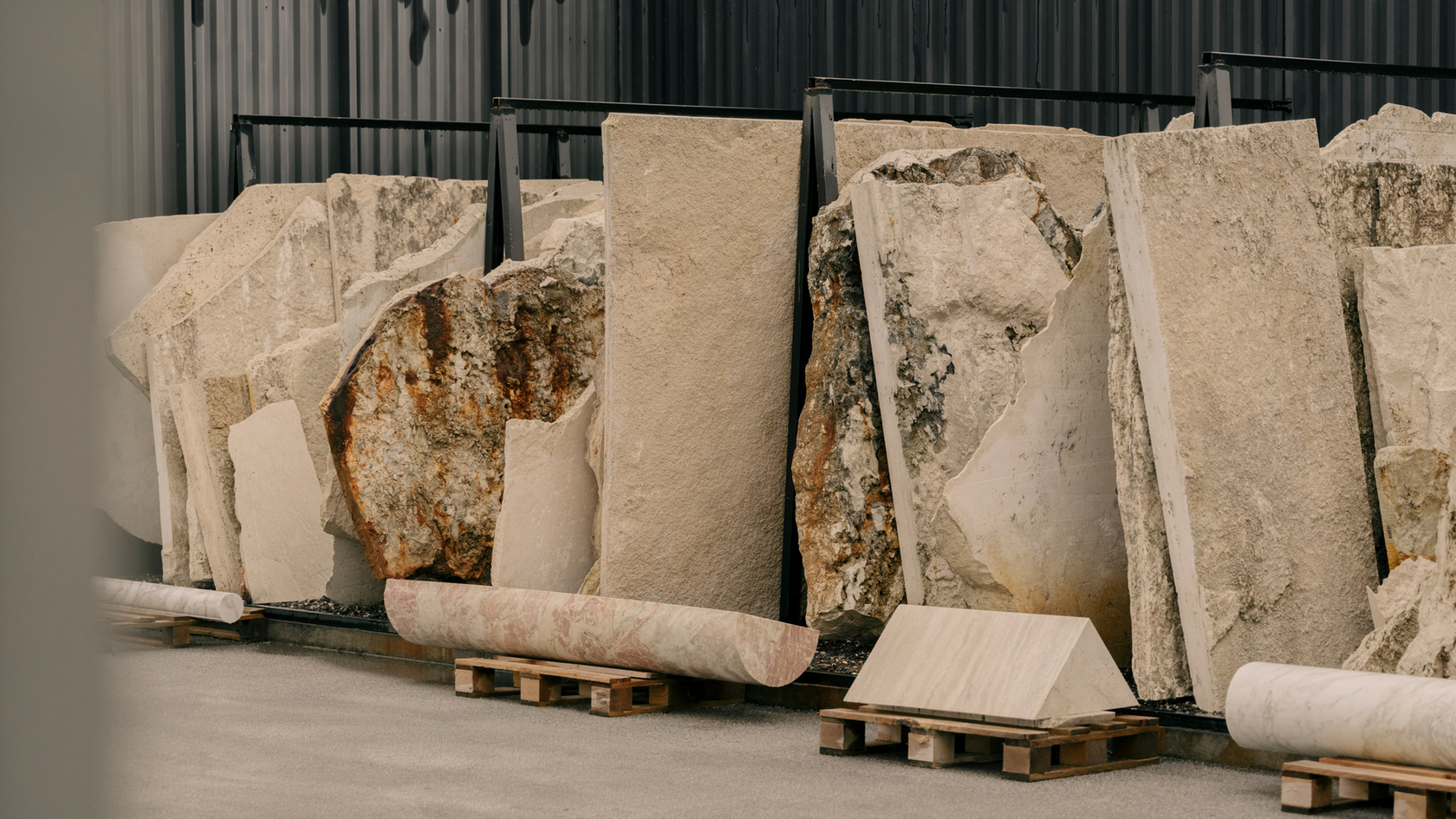 Storage with stacked natural stone slabs in front of a metal wall