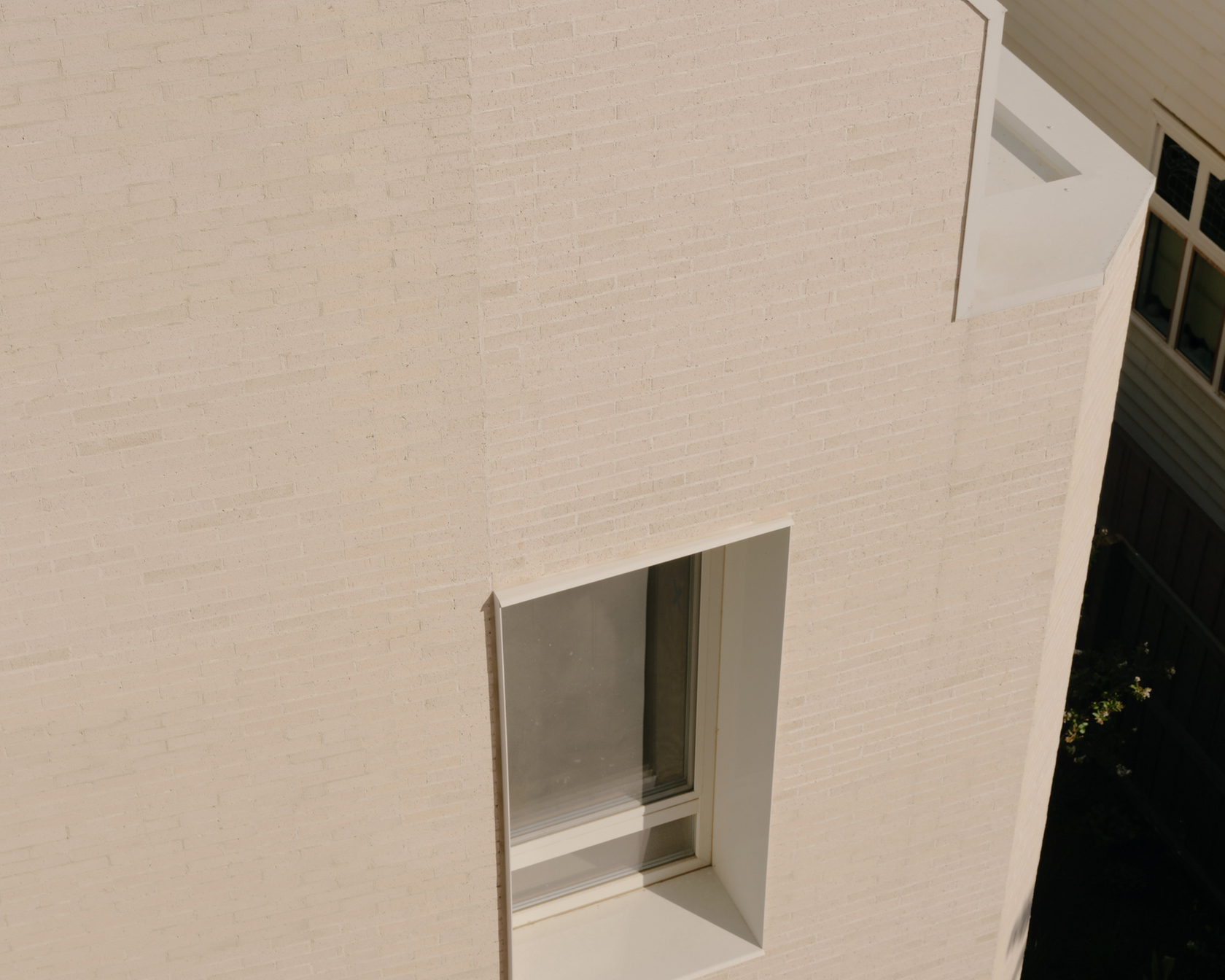 Minimalist white building façade with modern window openings and clear lines.