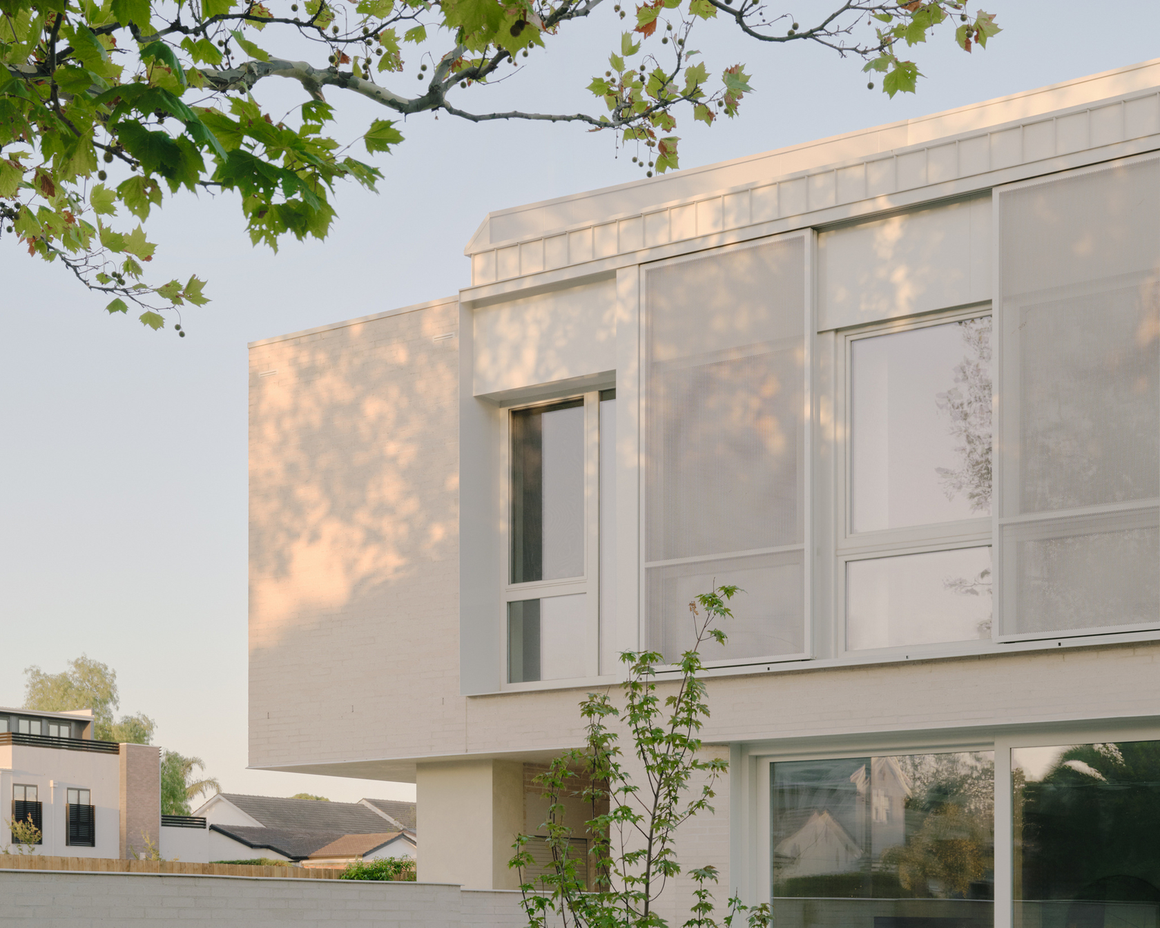Modern house with minimalist architecture and large windows in a green setting.