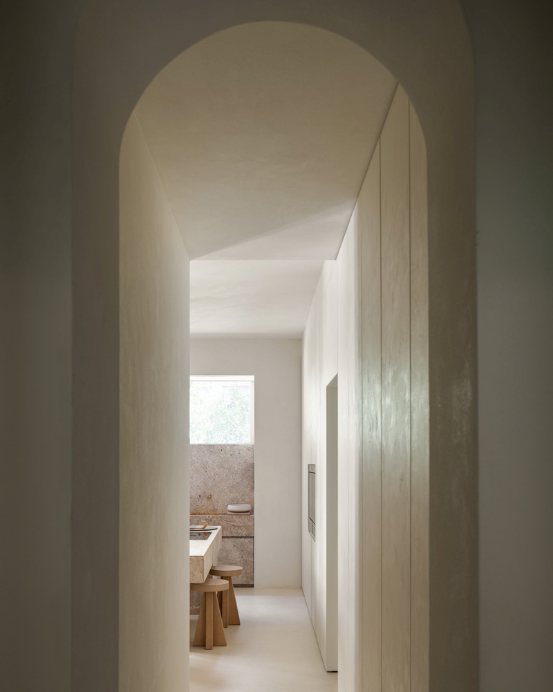Minimalist kitchen with natural light, warm wooden elements and modern appliances.