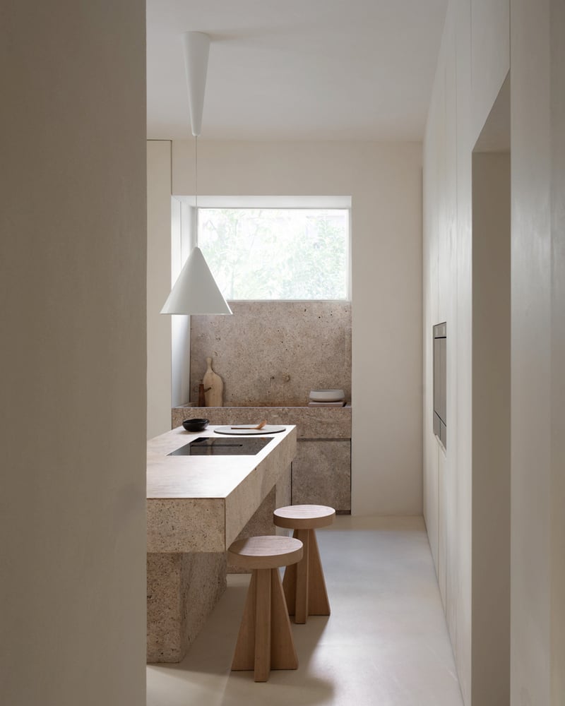 Minimalist kitchen with natural stone cooking island, wooden chairs and modern lighting