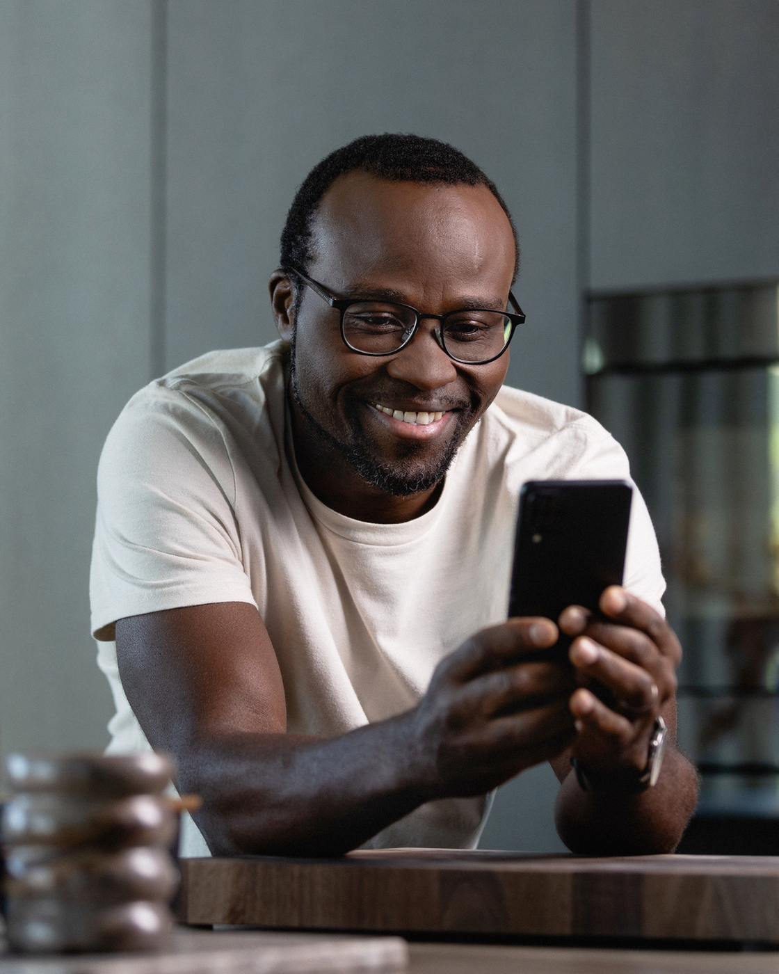 Mann mit Smartphone in einer modernen Küche mit stilvollen Geräten und minimalistischer Einrichtung.