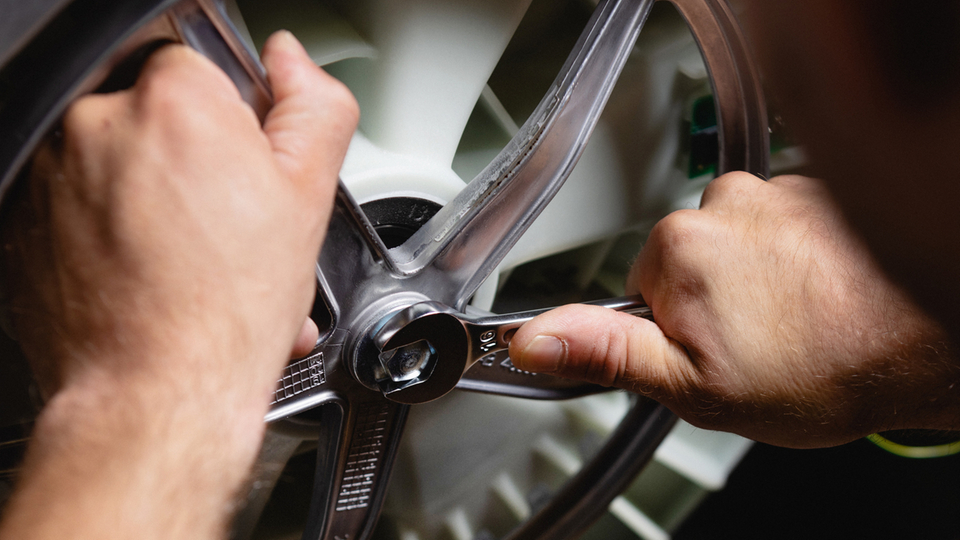 Technician repairs a washing machine with a wrench in close-up.