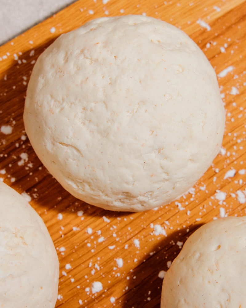Fresh dough balls on a floured wooden board, perfect for baking recipes.