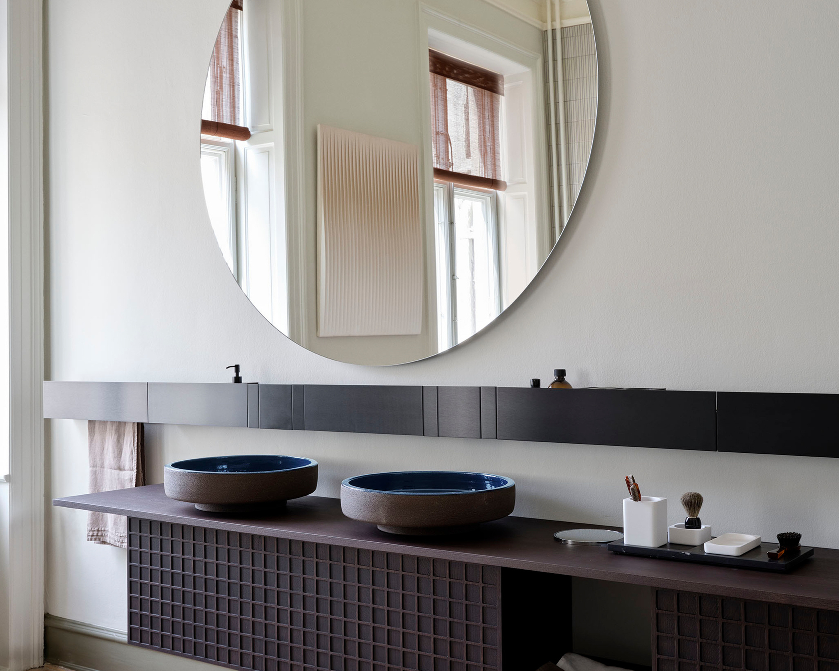 Modernes Badezimmer mit rundem Spiegel und zwei Waschbecken auf Holzkonsole
