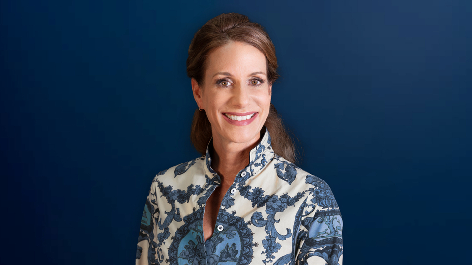 Frau in gemustertem Hemd vor blauem Hintergrund