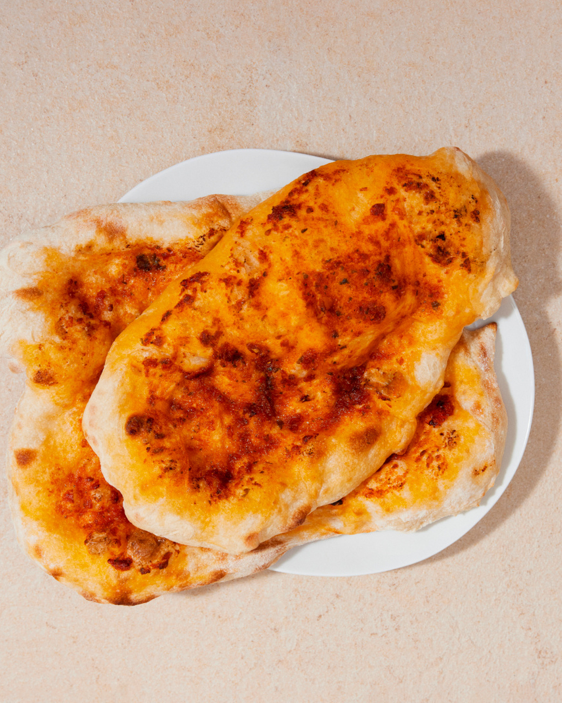 Freshly baked flatbread on a white plate, perfect for the kitchen or as inspiration for recipes.