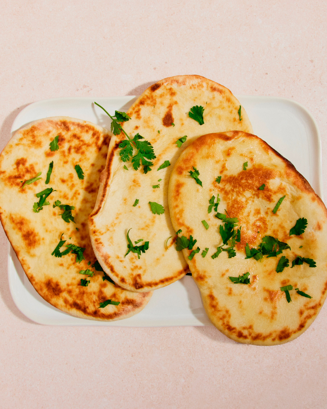 Naan Brot auf einem weißen Teller mit Koriander garniert