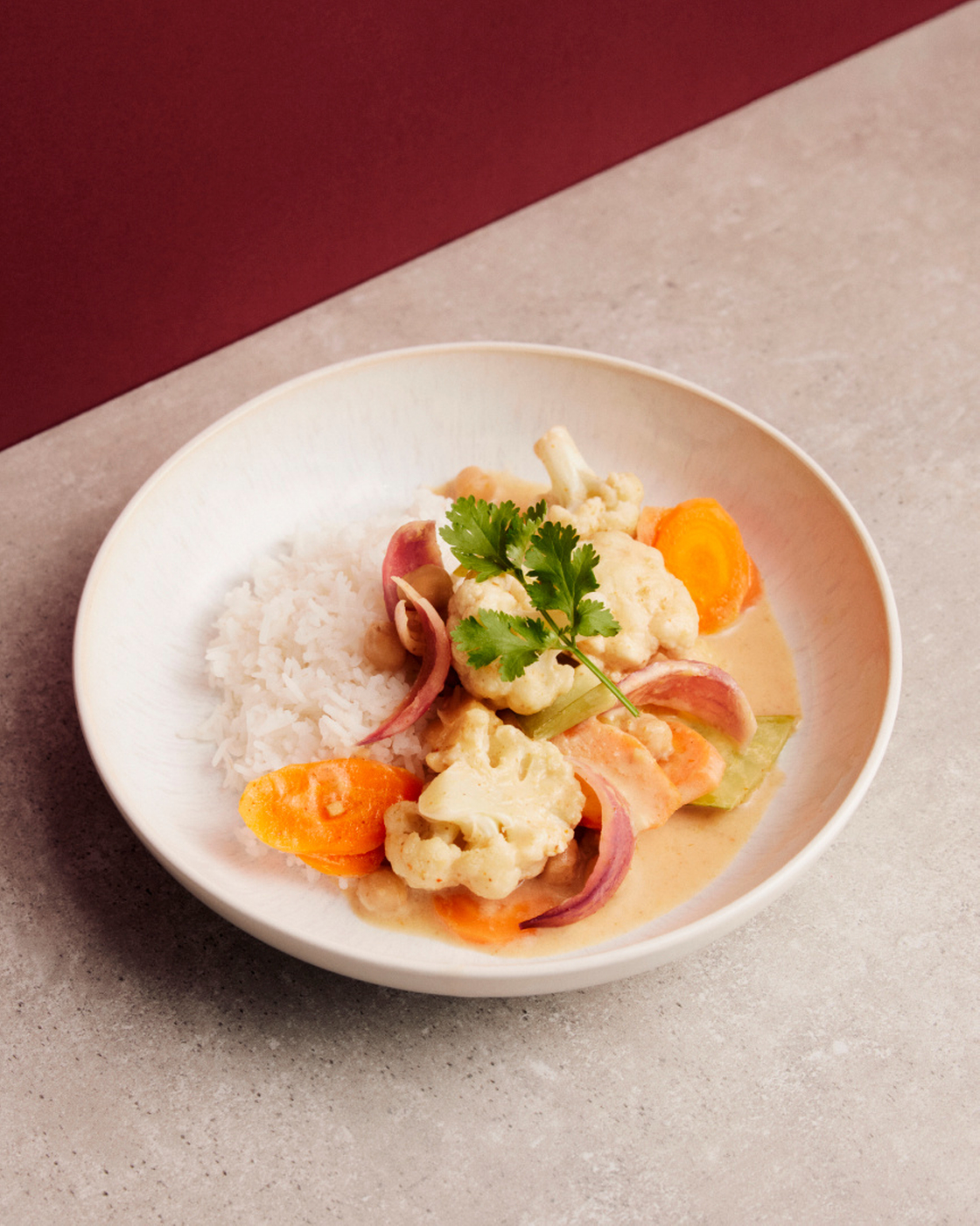 Vegetable curry with rice on a plate, served with fresh herbs.