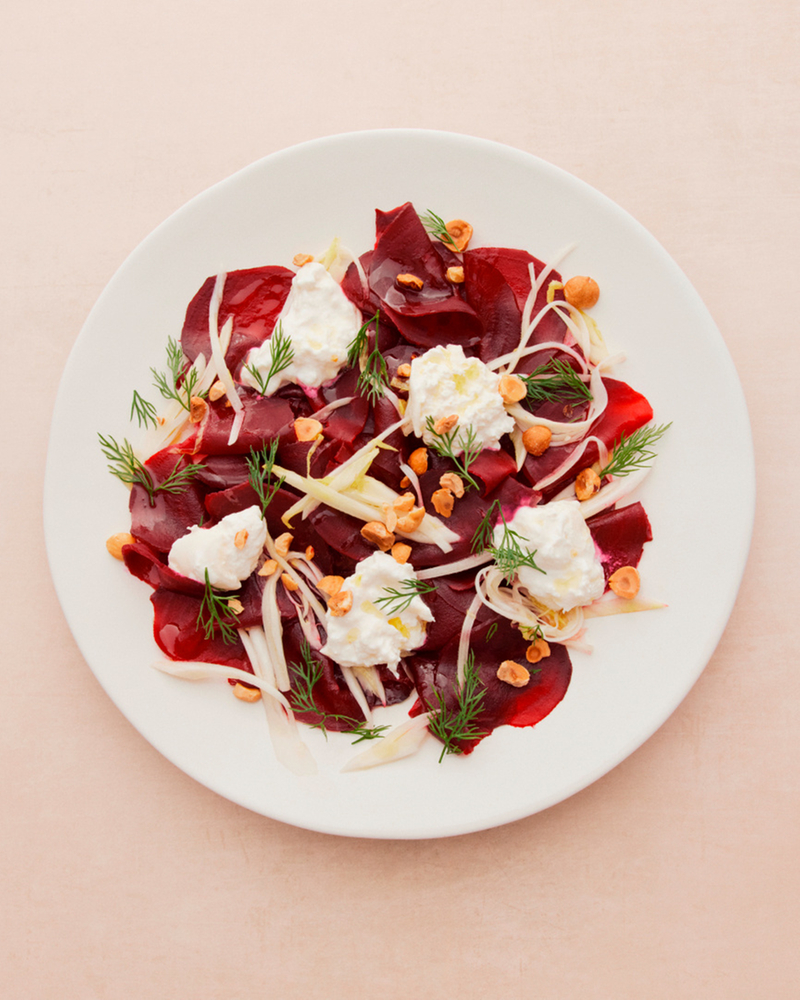 Beet carpaccio with cream cheese, dill and hazelnuts on a white plate