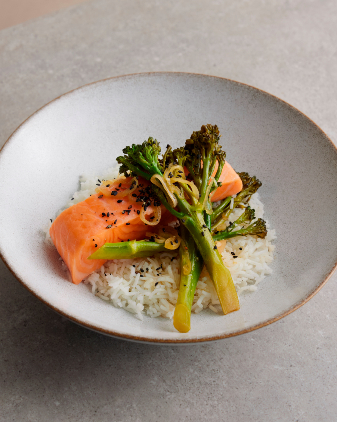 Steamed salmon with broccolini and rice on a plate, ideal for healthy cooking and inspiration.