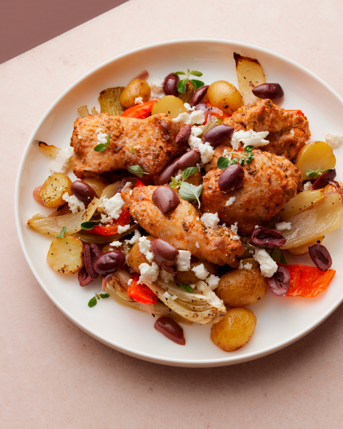 Mediterranes Hähnchen mit Kartoffeln, Paprika, Oliven und Feta auf einem Teller.