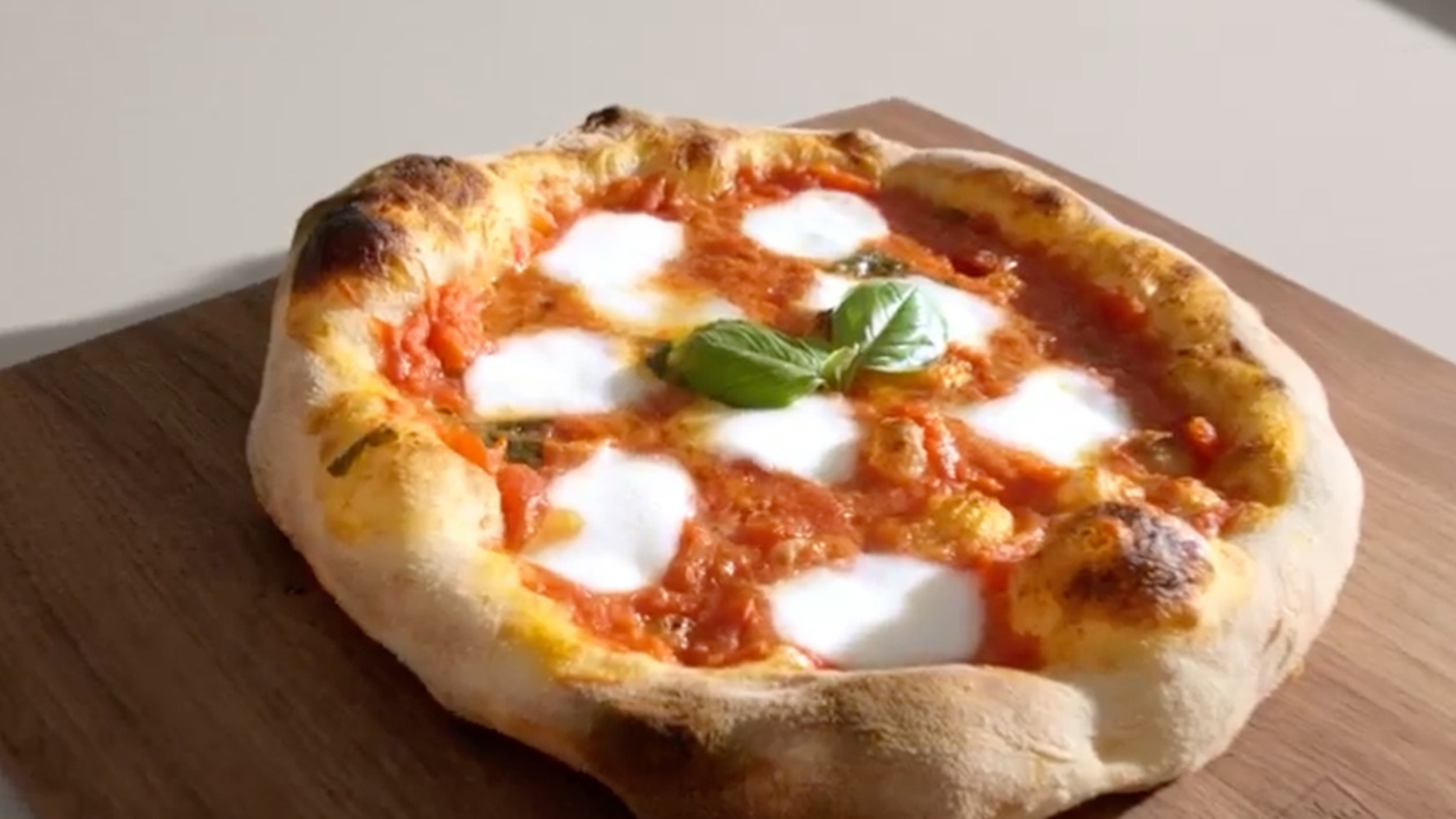 Freshly baked Margherita pizza with mozzarella and basil on a wooden board