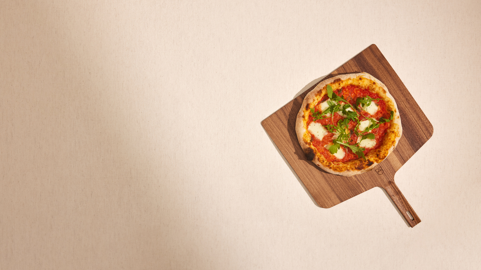 Pizza Margherita auf einem Holzbrett mit frischen Kräutern
