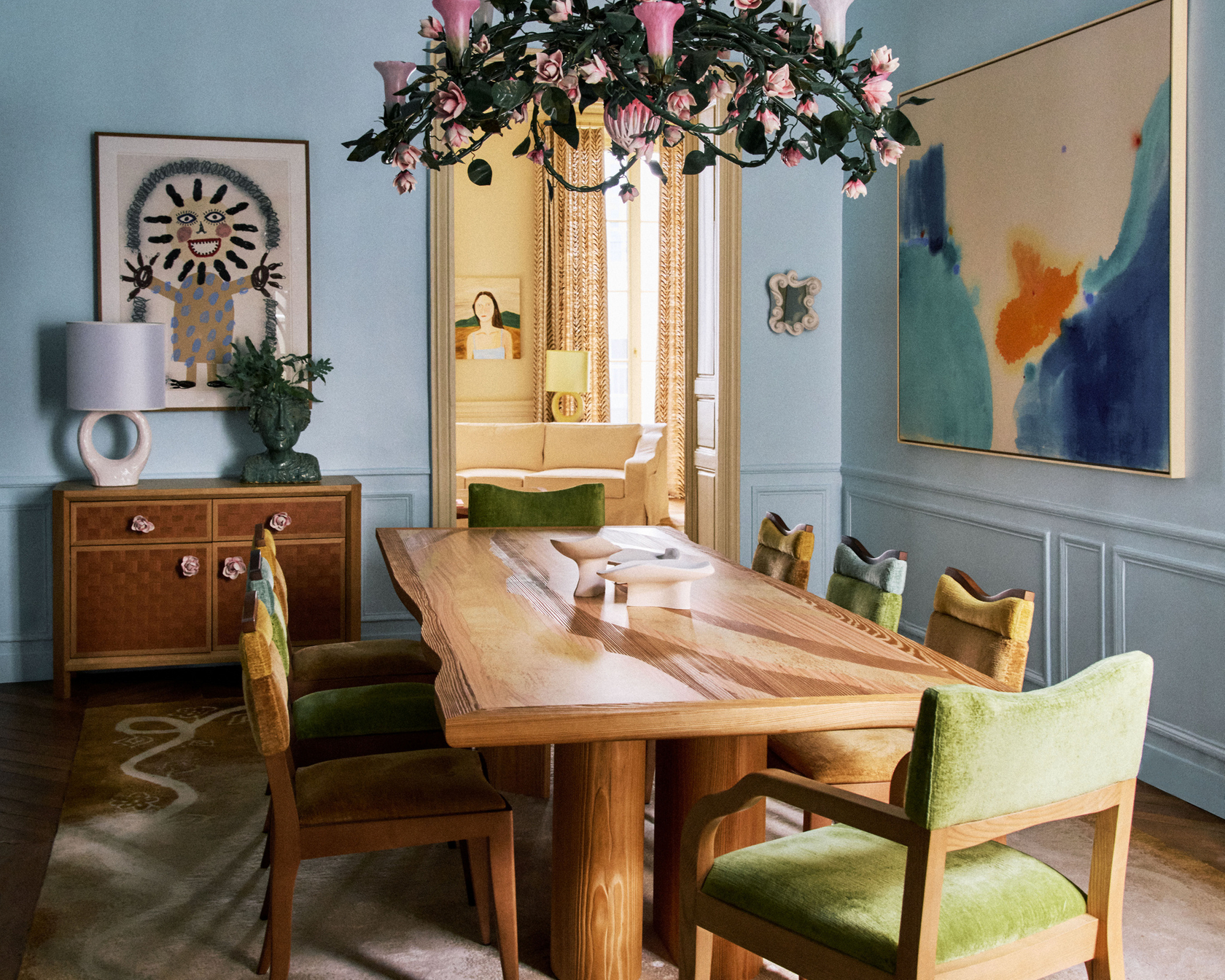 Dining room with wooden table, green chairs and decorative flower chandelier