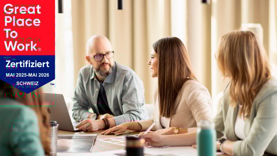 Teammeeting in einem Büro mit "Great Place to Work"-Zertifikat für die Schweiz, gültig von Mai 2025 bis Mai 2026.