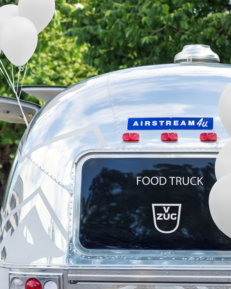 Food Truck avec logo V-ZUG et ballons blancs devant des arbres