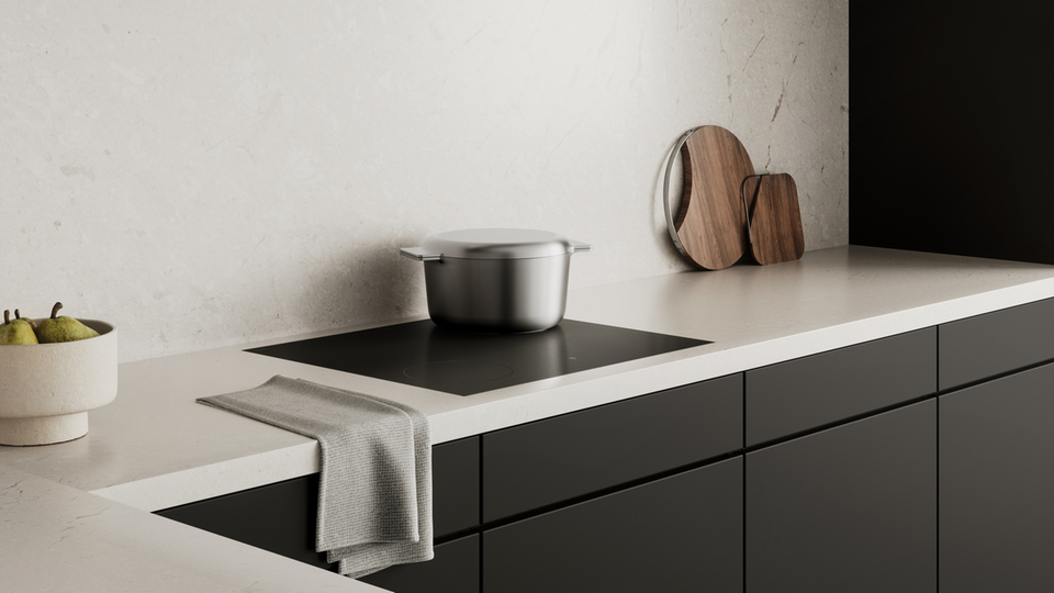 Cucina moderna con piano cottura a induzione, cappa aspirante e dettagli di stile come taglieri e fruttiere.