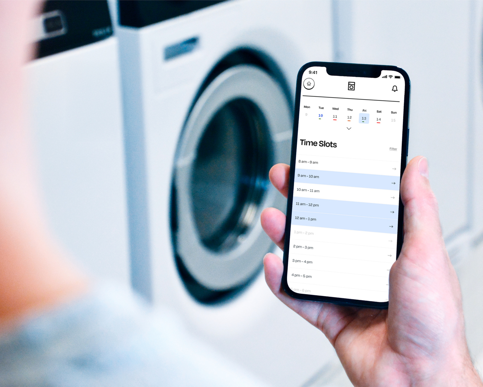 Smartphone with app for controlling washing machines in front of a series of washing machines.
