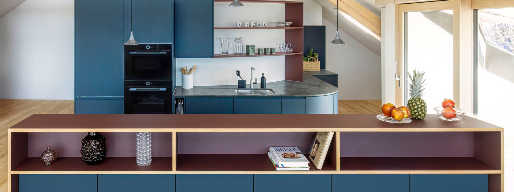 Modern kitchen with blue cabinets, wooden details and integrated appliances in an open space